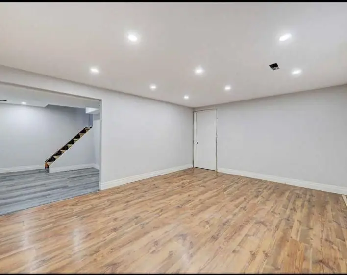 Basement with white walls and hardwood